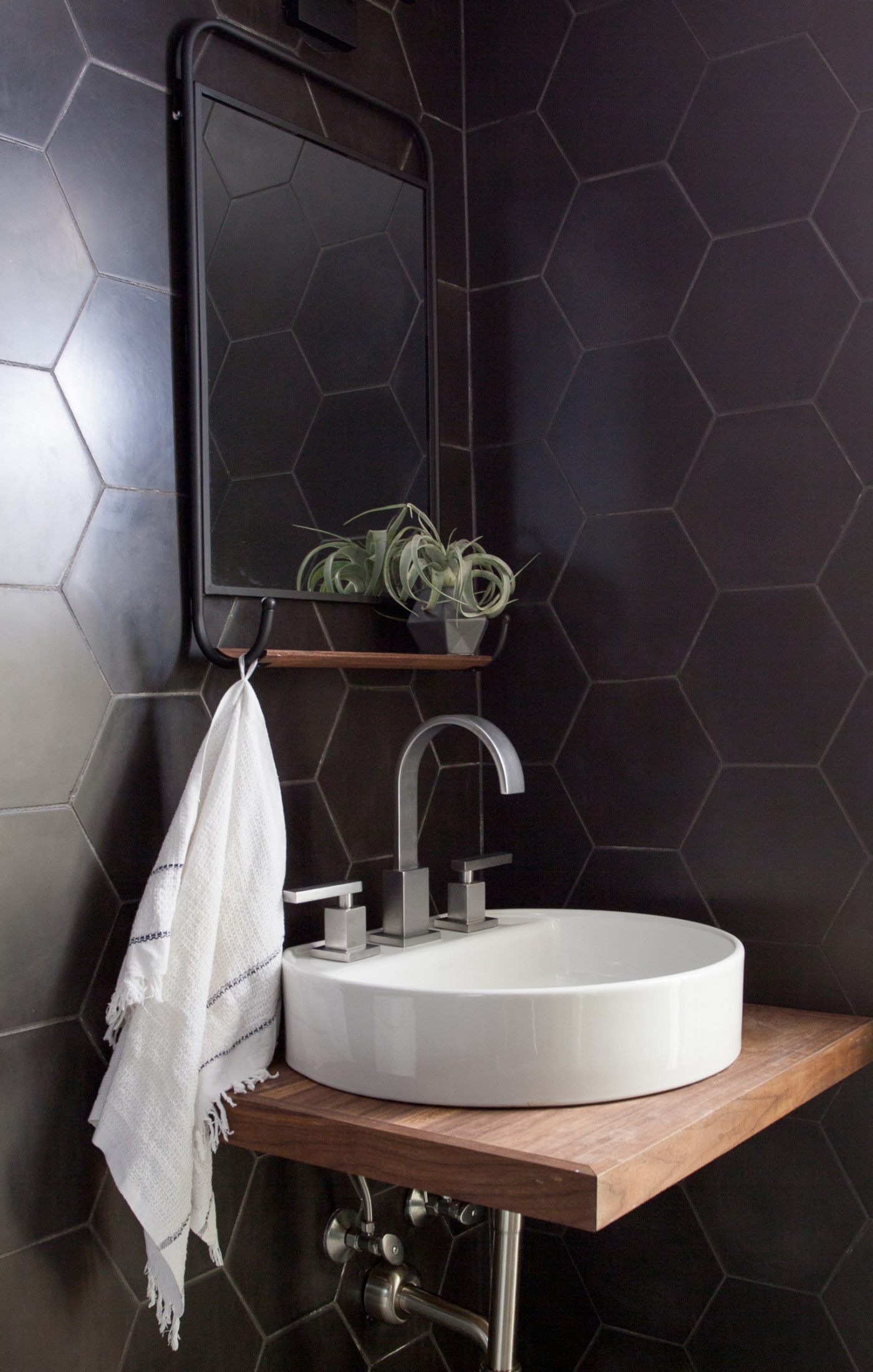 a bathroom with black hexagon tiled walls and a sink.