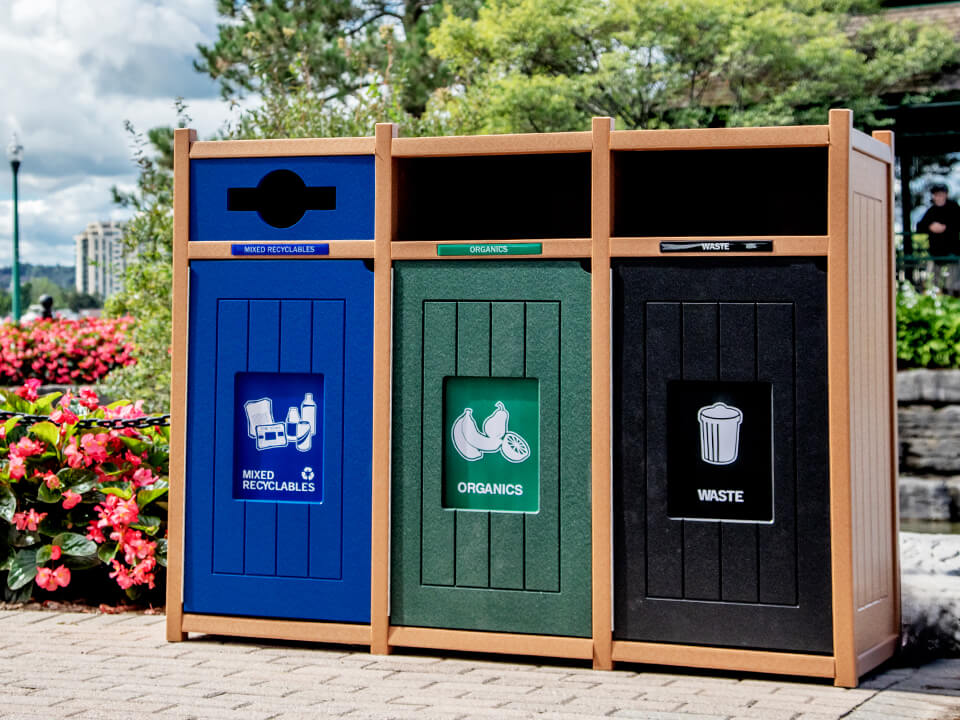 recycling and waste collection container made from recycled plastics in a city park with flowers and trees