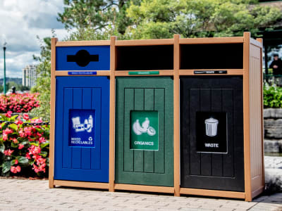 recycling and waste collection container made from recycled plastics in a city park with flowers and trees