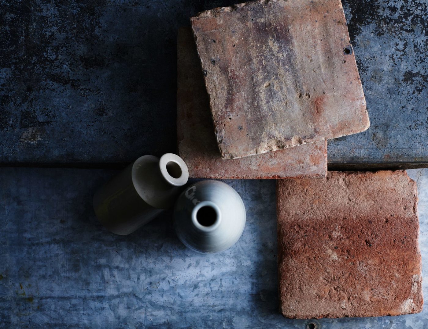 three terracotta tiles and two vases of a table.