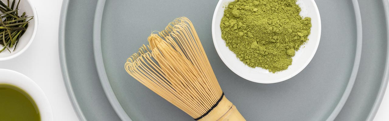 Table with Matcha Green Tea Powder Next to a Matcha Tea Whisk