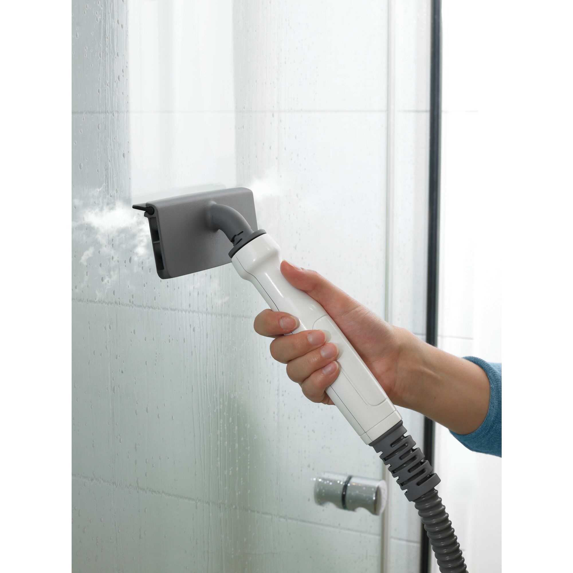 8 in 1 complete steam cleaning system being used to clean glass door in bathroom.
