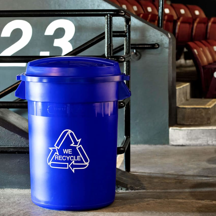 big capacity recycling container with we recycle printed on the side in a sports stadium
