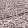 Brown-dot jacquard fabric, folded once with overlapping edge; dots form concentric circular patterns, slightly raised texture, photographed in close-up under neutral studio lighting on a pale background.