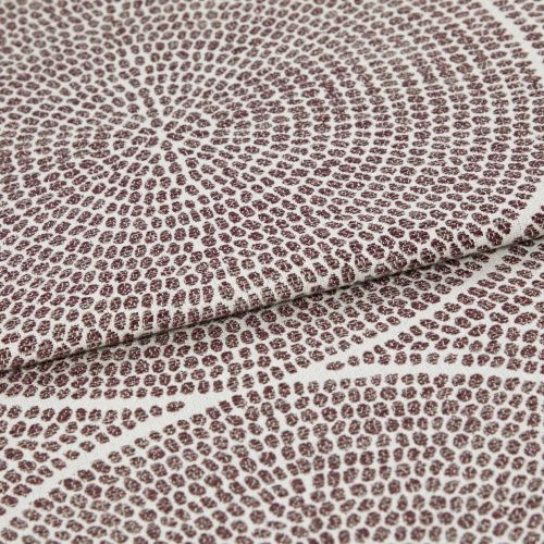 Brown-dot jacquard fabric, folded once with overlapping edge; dots form concentric circular patterns, slightly raised texture, photographed in close-up under neutral studio lighting on a pale background.
