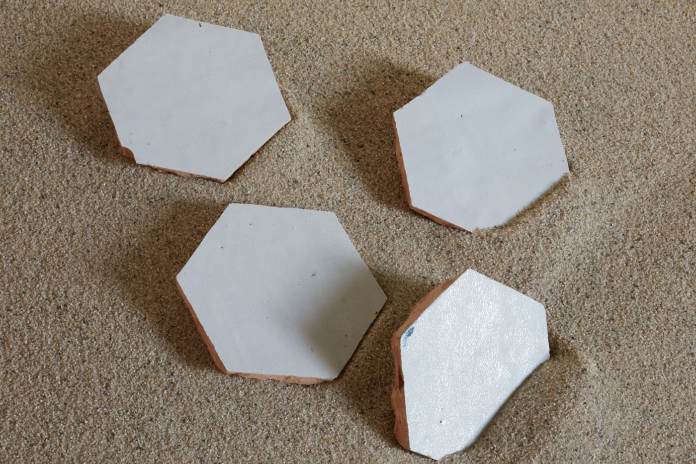 a set of white hexagon tiles on the sand.