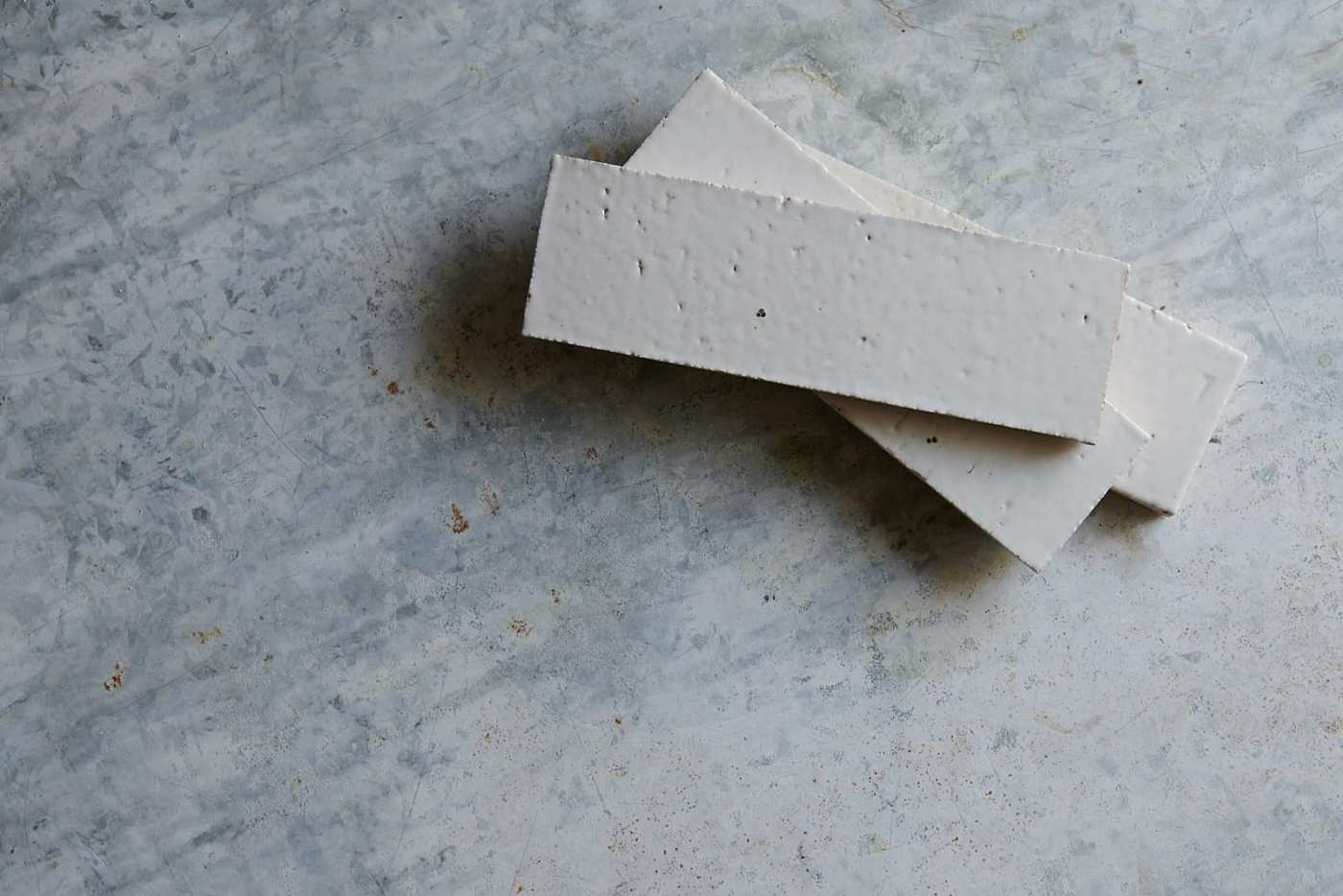 three grey rectangle tiles on top of a concrete surface.