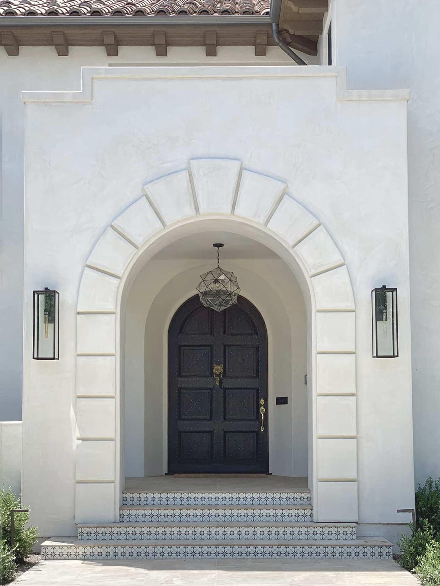 a white house with a black door and archway.