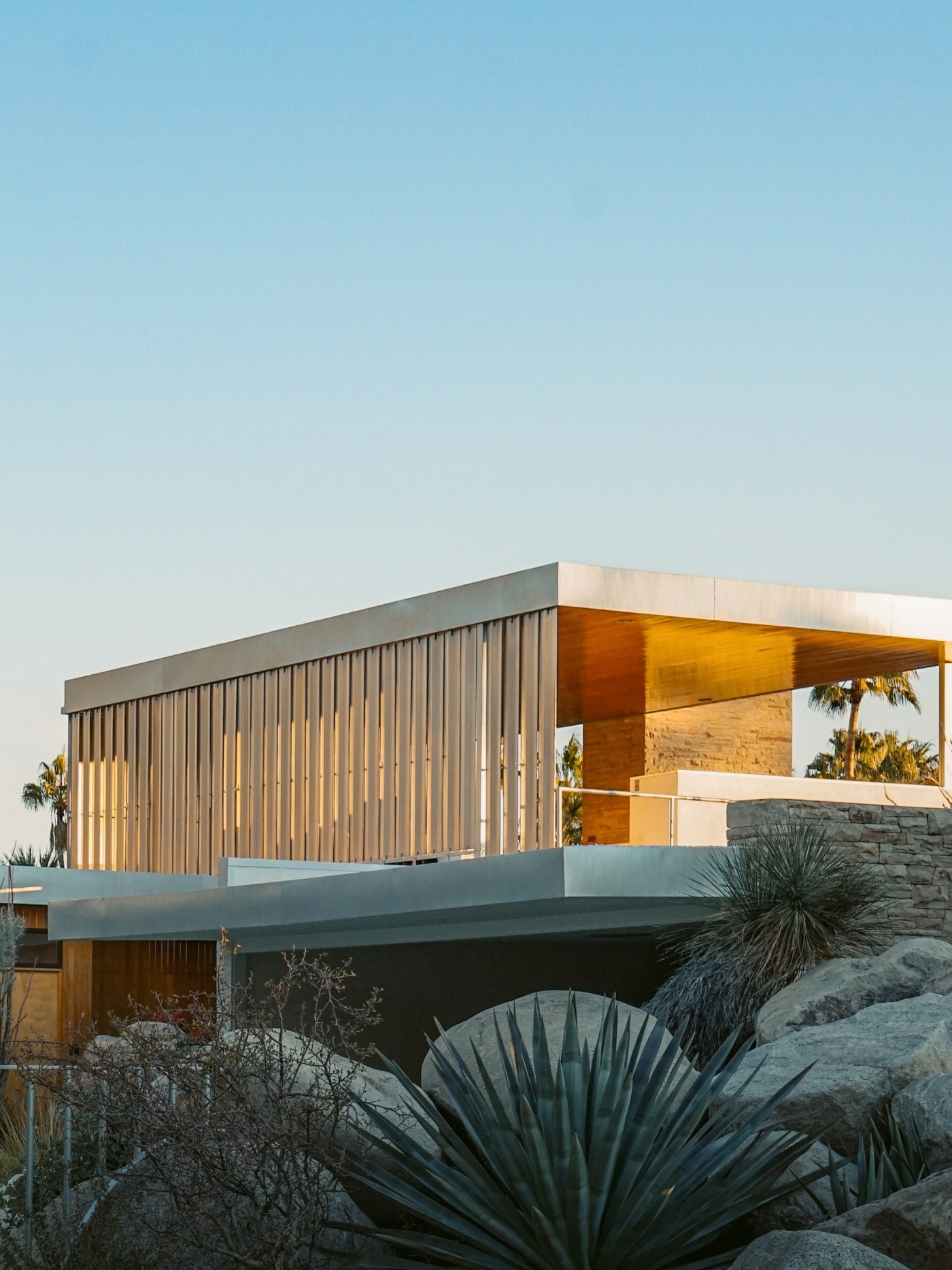 a modern house surrounded by rocks and cactus.