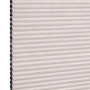 Cellular pleated window shade (honeycomb design) fully lowered, pale blush fabric with visible black cell openings at left edge, blocking light; close-up view against a neutral background.