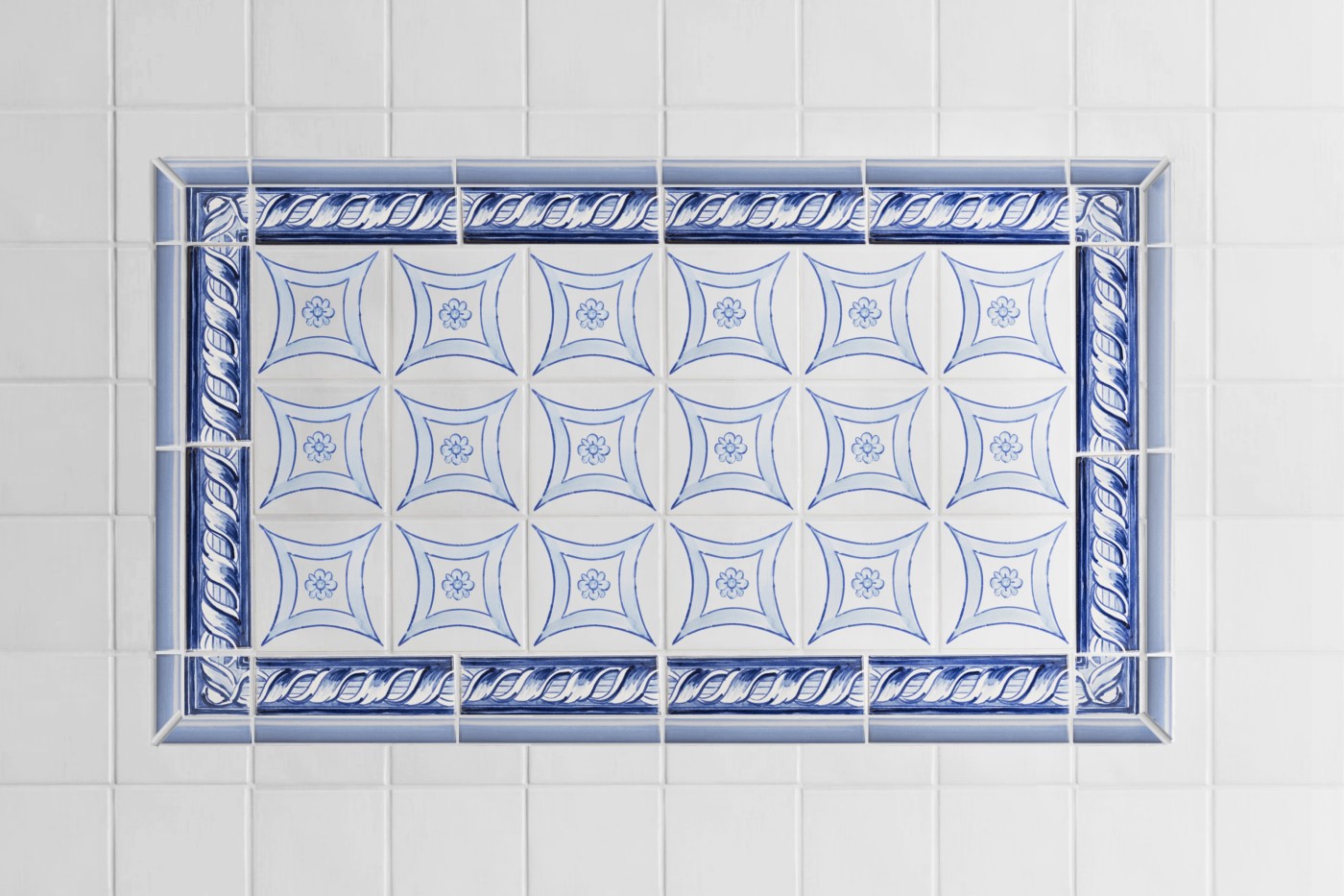 a blue and white tile pattern with a border in a bathroom.