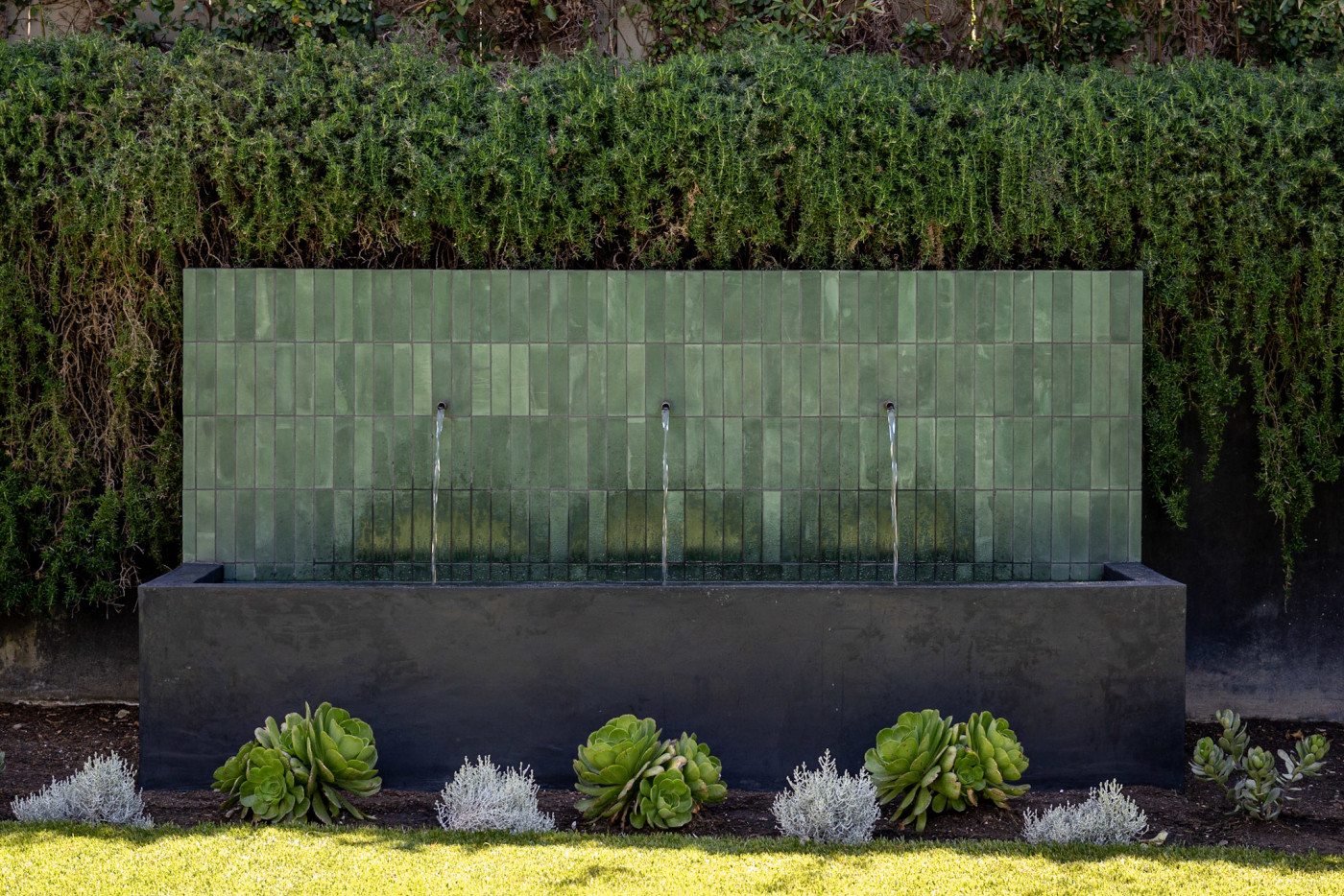 a green tiled water feature in a garden.