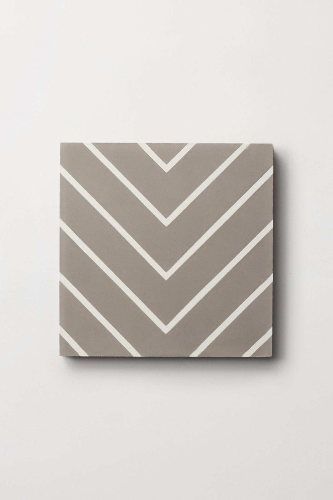 a square tile with a gray and white chevron pattern on a wall.