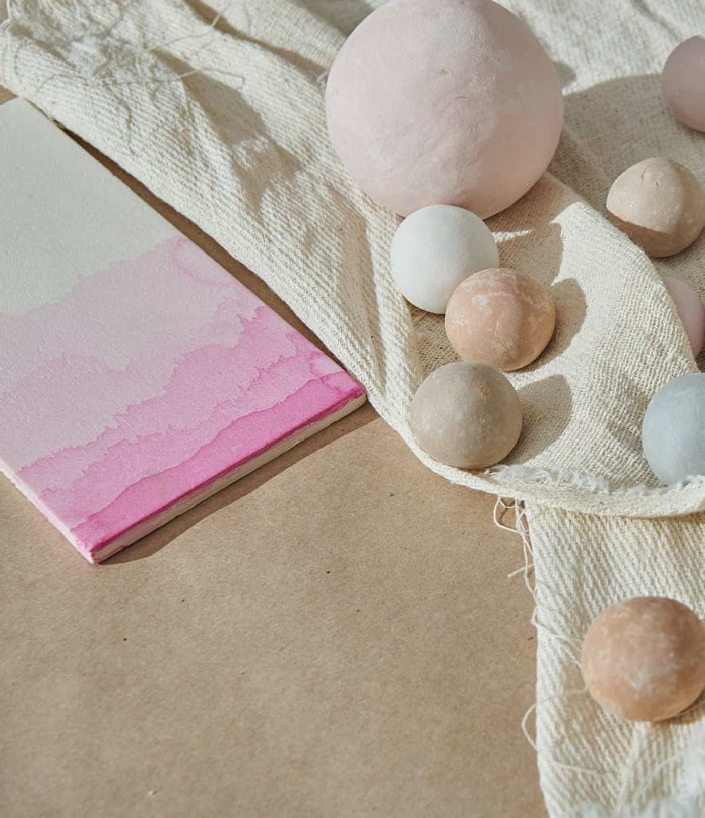 a pink and white patterned tile and round ceramic pieces on a piece of cloth.