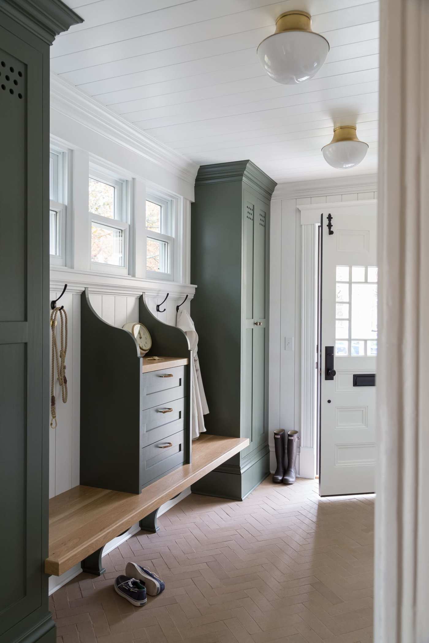 a mudroom with green cabinets and a wooden bench.