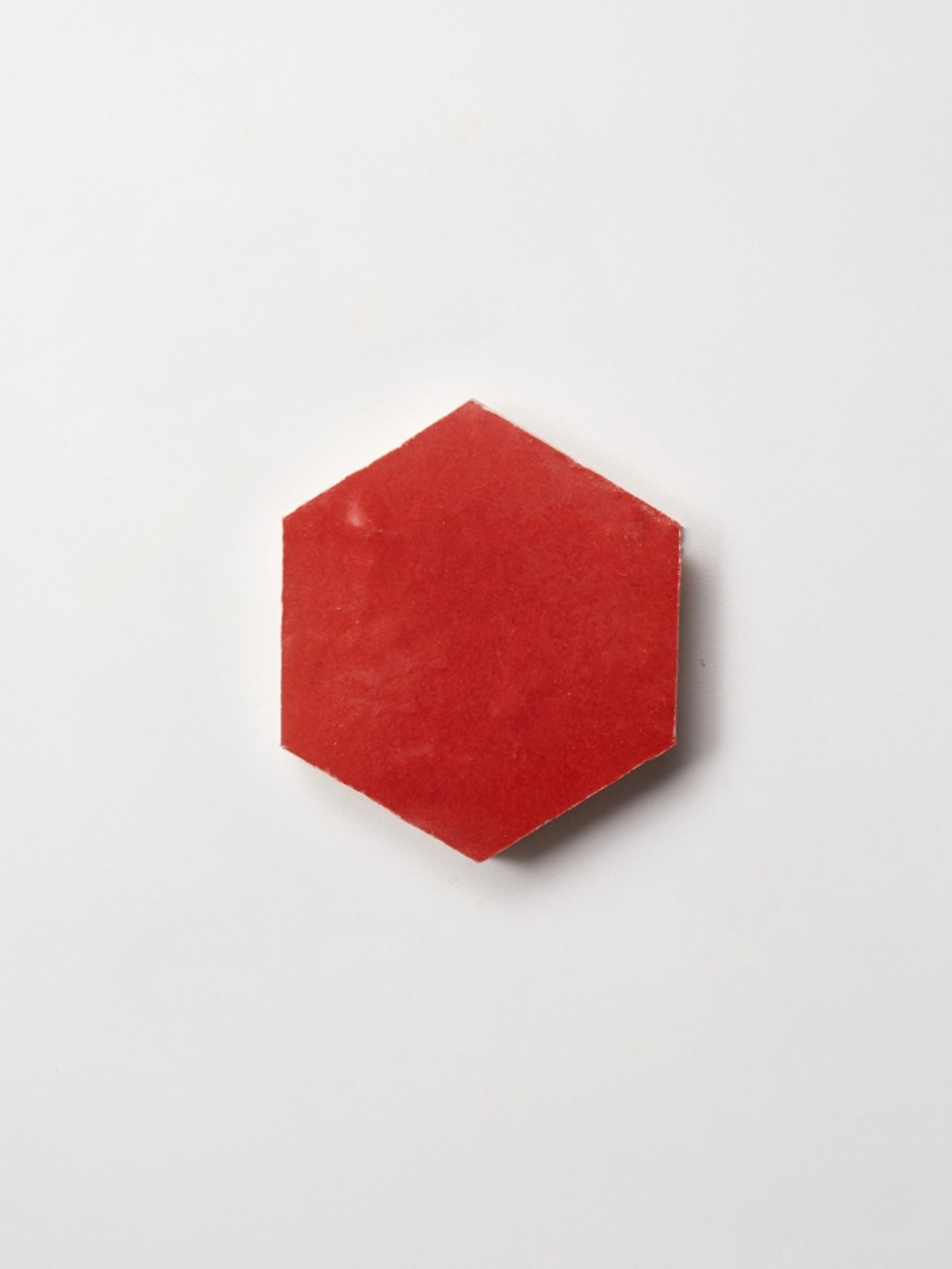 a red hexagonal tile on a white surface.