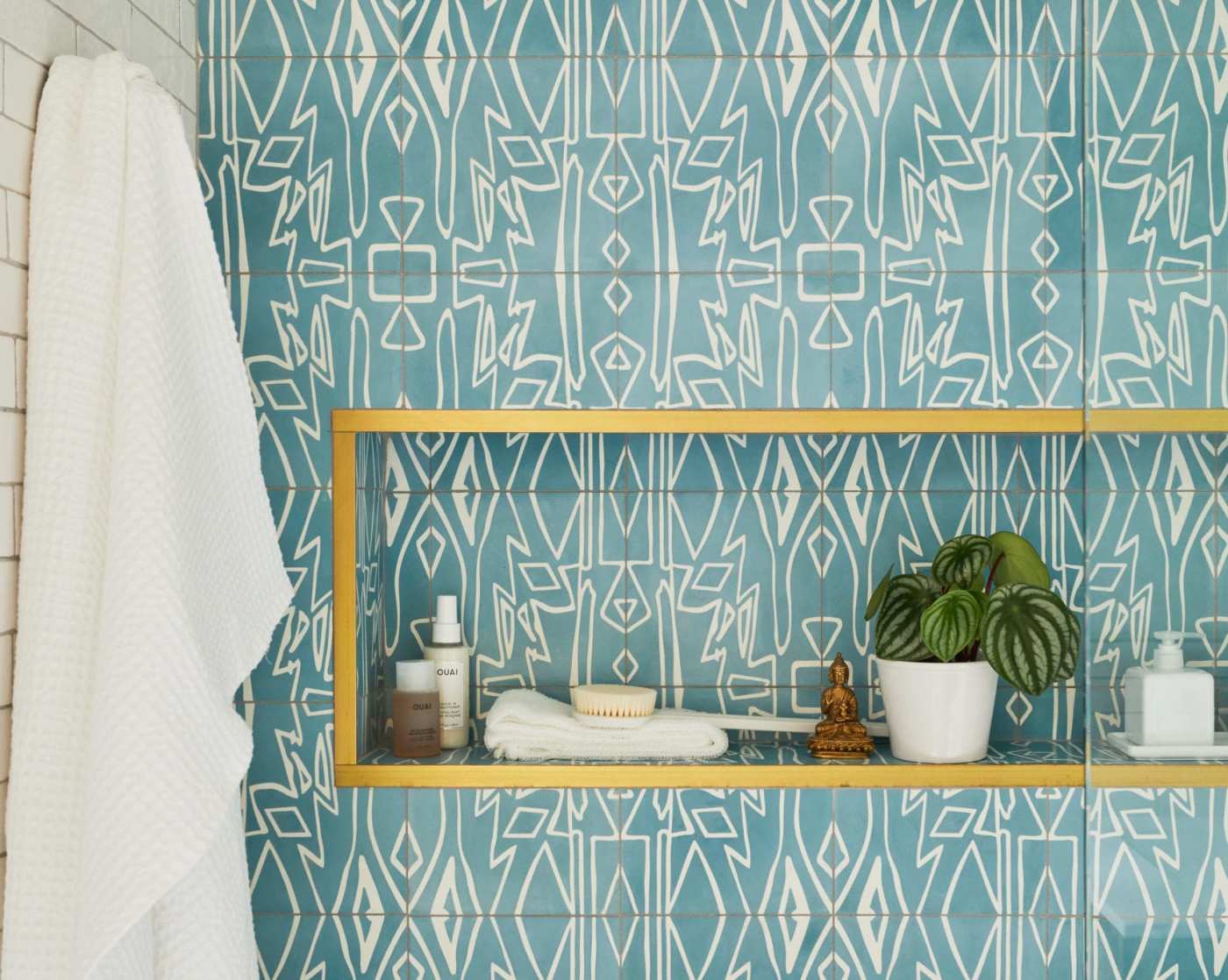 a bathroom with a blue tiled wall and a gold shelf.