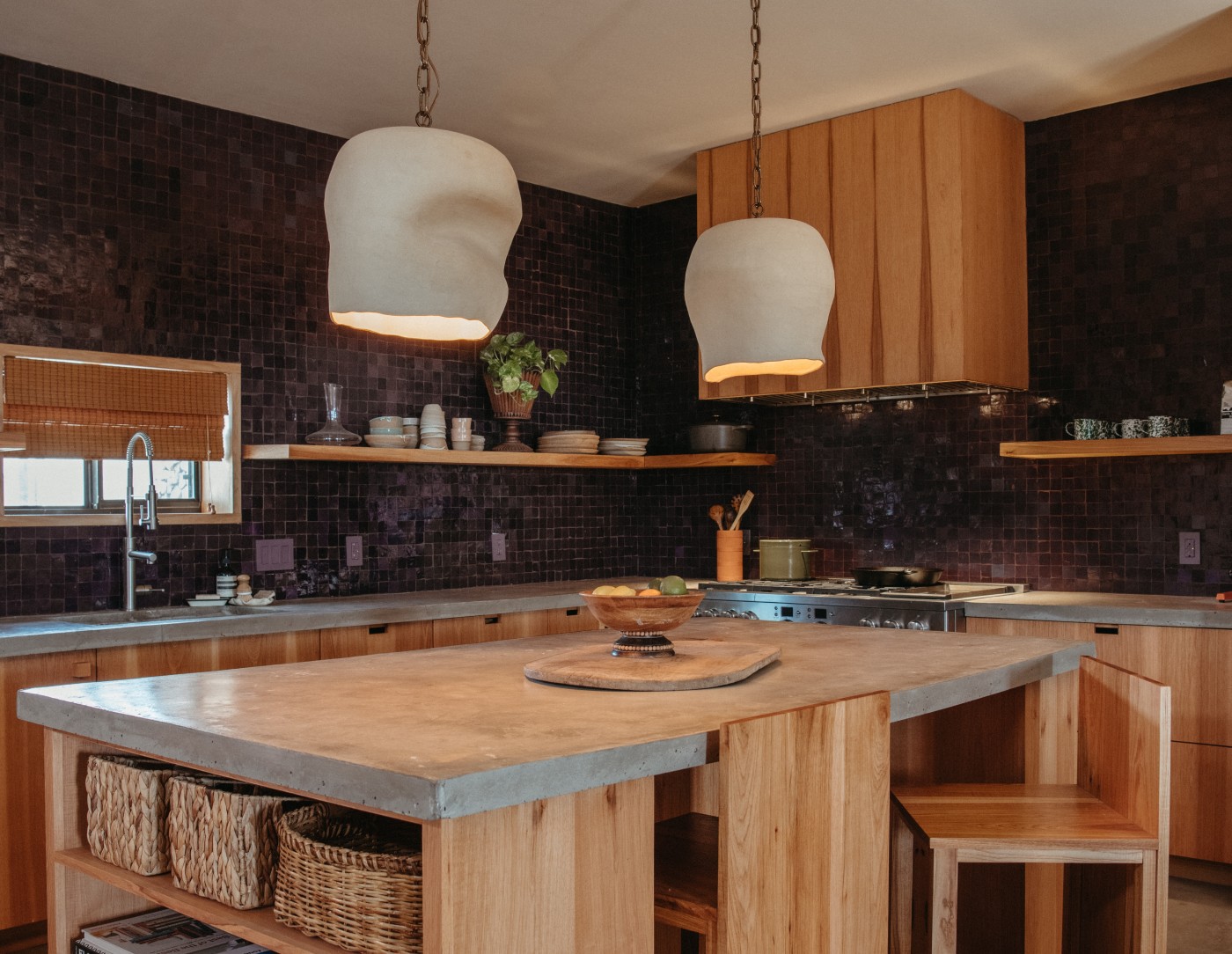 a kitchen with a wooden island and black tiled walls.