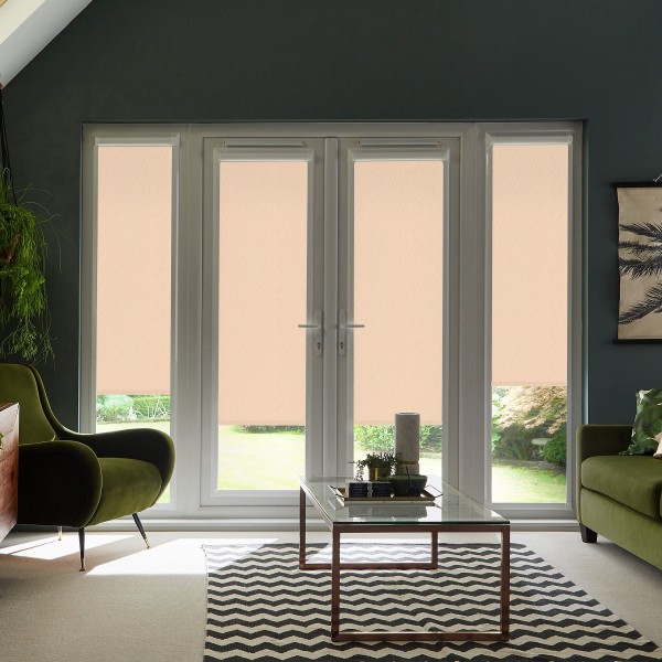 French doors with beige roller blinds partially lowered, framing a sunlit garden; green armchairs and a glass coffee table sit on a black-and-white chevron rug in a living room.