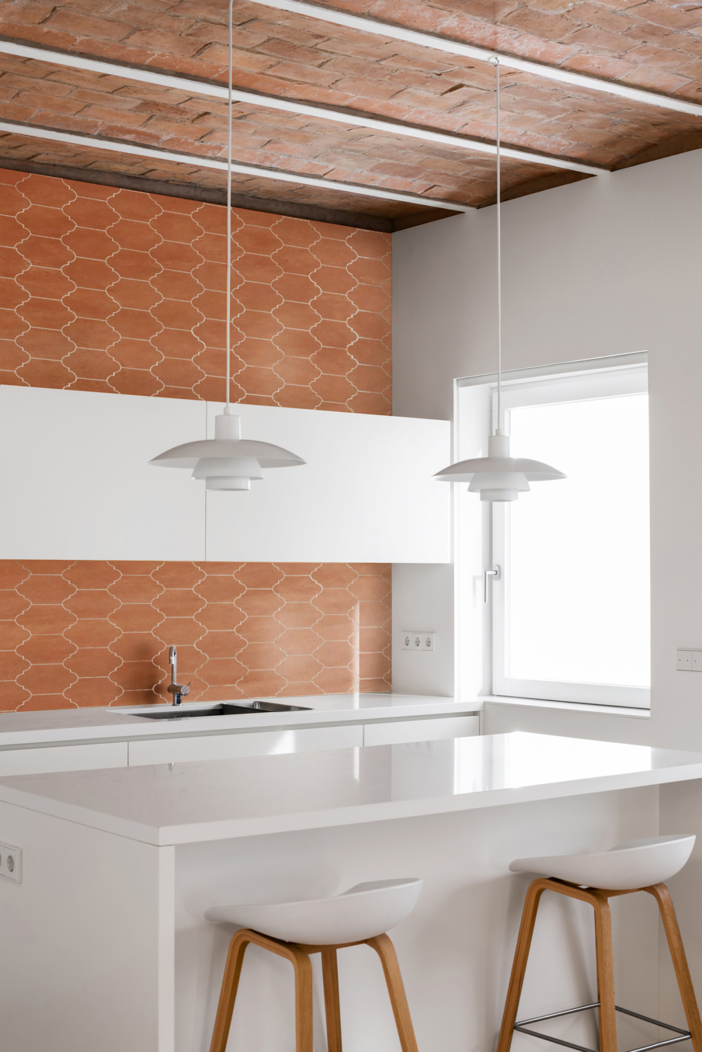 a white kitchen with a wooden ceiling.