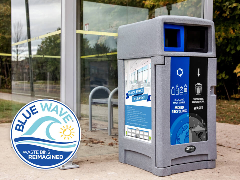 grey plastic outdoor durable recycling and waste container with front locking door and large body signage sitting outside beside a municipal bus shelter