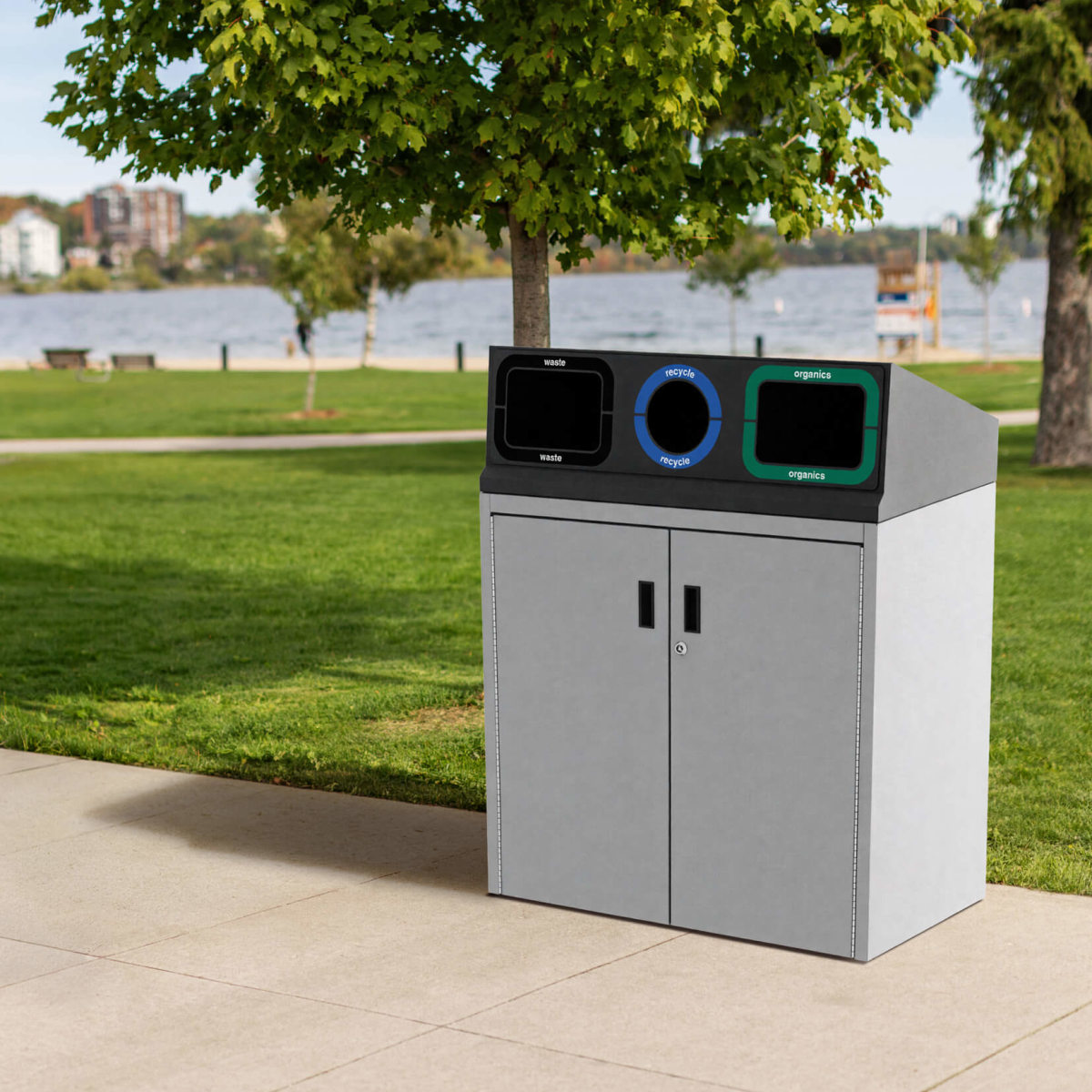 all metal waste and recycling bin with custom lid labels along a waterfront sidewalk on a sunny day