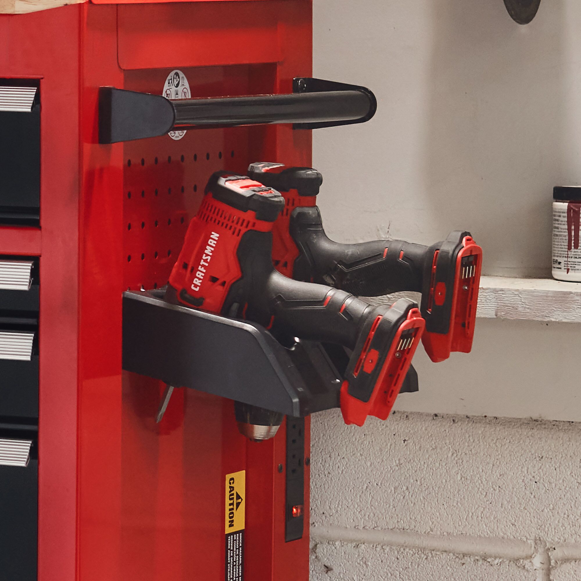 Close-up view of 2 CRAFTMAN® Drills stored in holder on side of metal storage cabinet