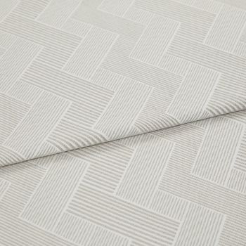 Cream textured fabric with raised linear herringbone rectangles, folded and overlapping across the frame, showing ribbed weave detail in a close-up product shot with soft, diffuse lighting.