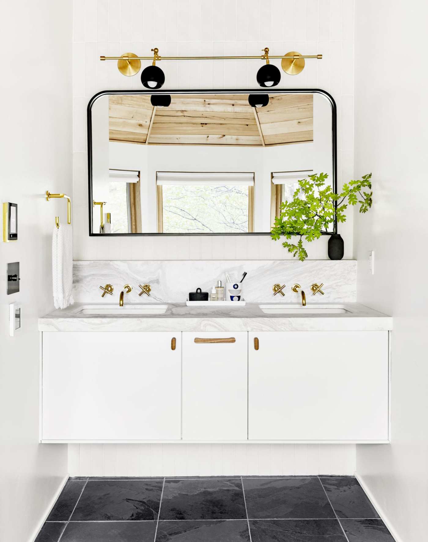 a white bathroom with a black tile floor and a mirror.