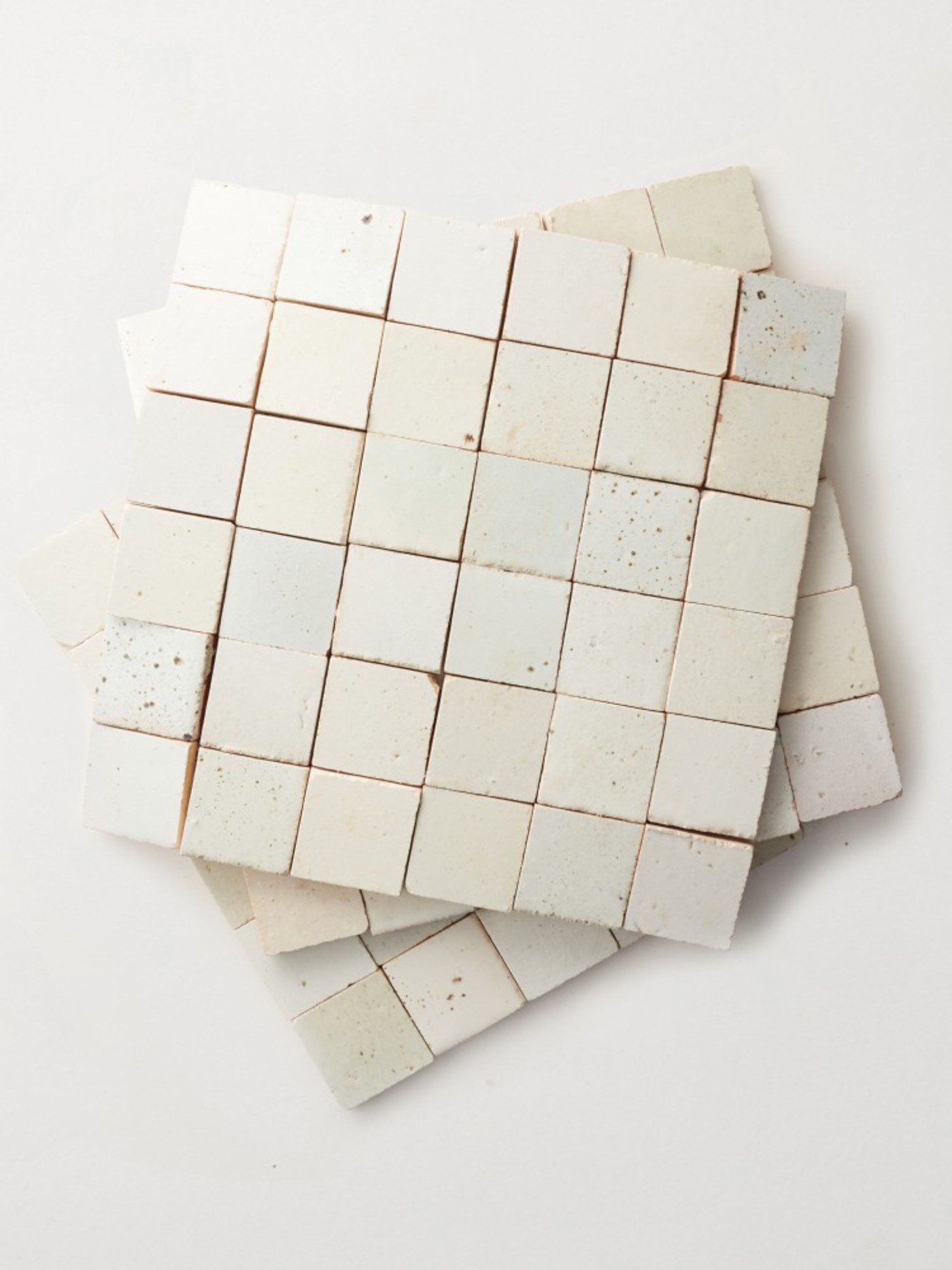 a stack of white tile sheets on a white surface.