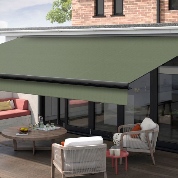 Green retractable fabric awning, fully extended with black front bar, shading ground-floor glass patio doors; outdoor terrace with wicker armchairs, round coffee table, cushioned bench and brick façade in daylight.