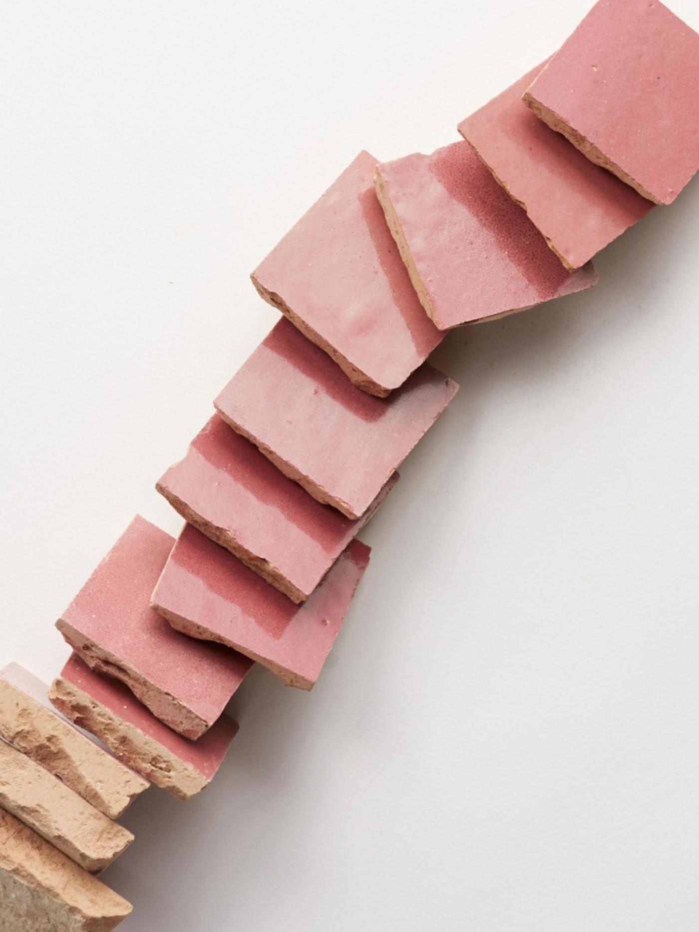 a stack of pink square tiles on a white surface.