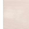 Cellular (honeycomb) pleated blind, cream-colored, fully lowered and closed with visible hexagonal cells; diffusing soft light across a plain interior wall, suggesting a bright, neutral room.