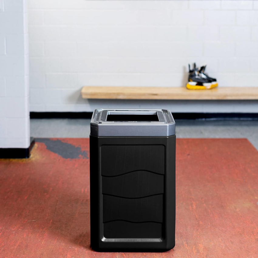 large trash container made from durable 100% recycled plastic body with a stainless steel looking lid inside a hockey locker room