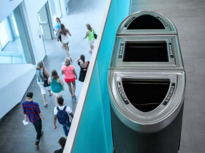 triple all black bodies trash and recycling collection containers with brushed pewter lids in a busy college campus