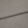 Gray boucle upholstery fabric folded to show an overlapping edge; dense looped texture; close-up, evenly lit studio view of a neutral-colored textile surface.