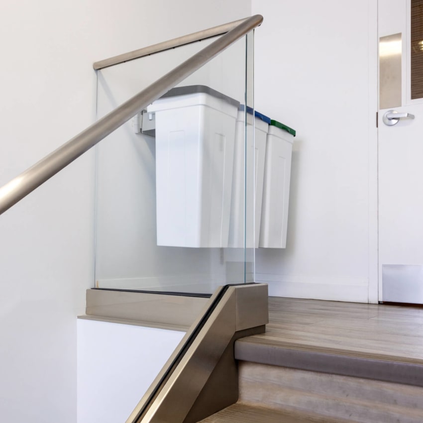 triple waste and recycling bins hanging on the wall at the top of a staircase