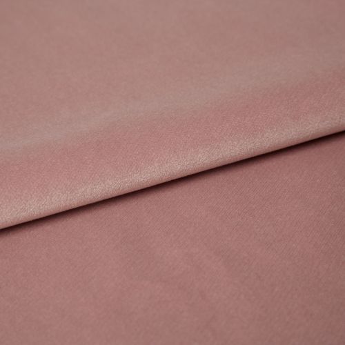 Dusty-rose velvet fabric folded across the frame, overlapping with a visible crease; its nap catches soft highlights in a close-up studio view on a flat surface.