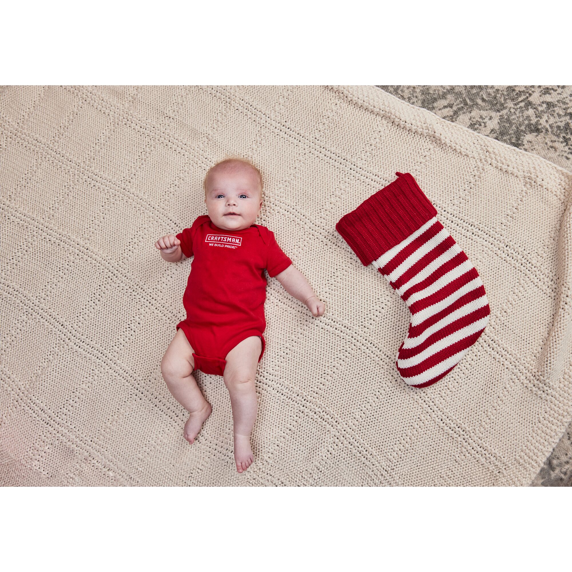 Front View of Baby in CRAFTSMAN Onsie next to Christmas stocking