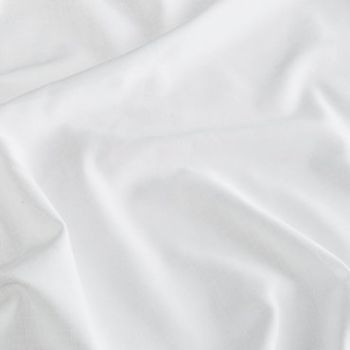 White satin fabric spread across a surface, rumpled into gentle folds and creases that catch soft diffuse light, close-up view with a neutral background.