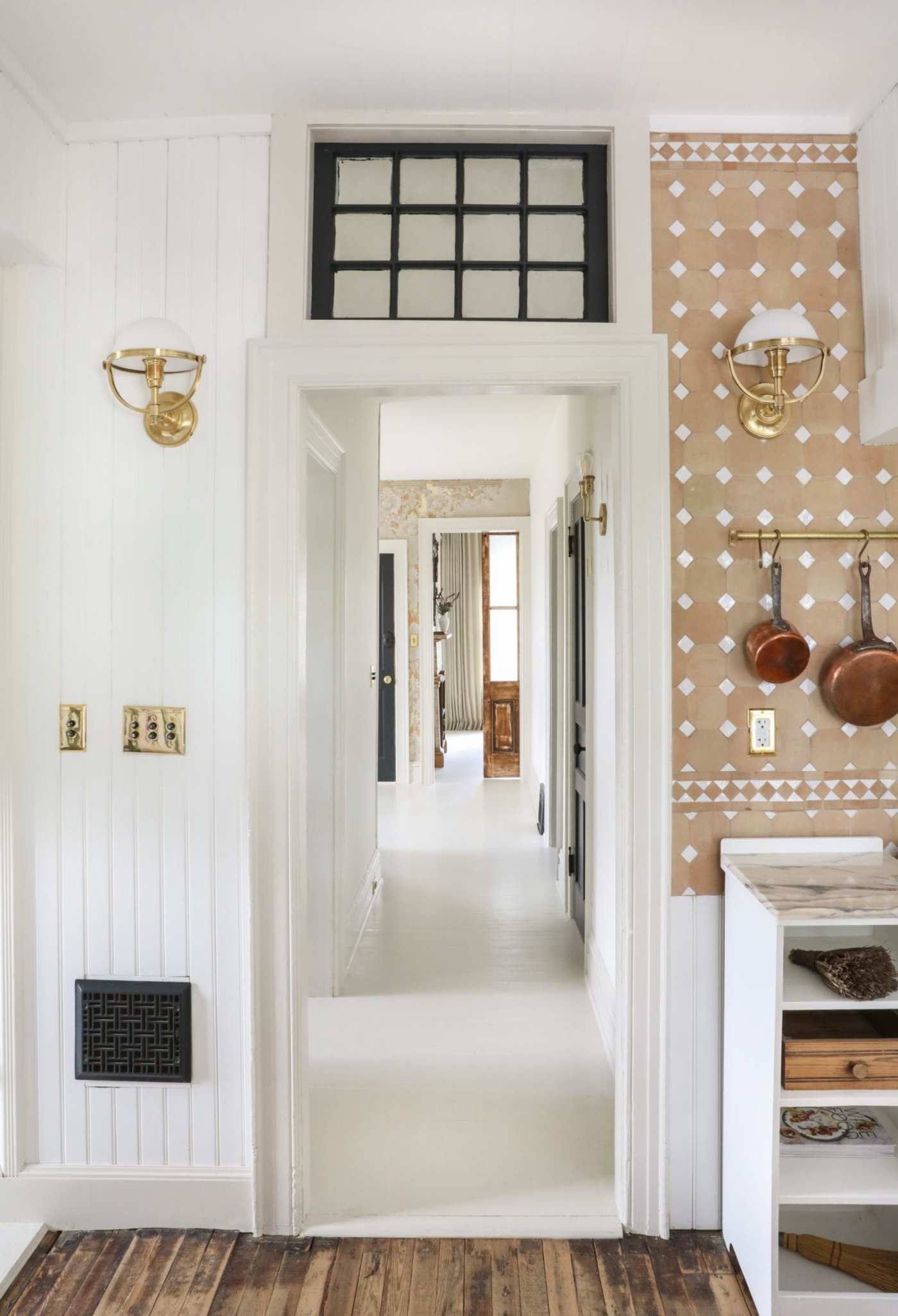 a white kitchen with wooden floors and a tile backsplash.