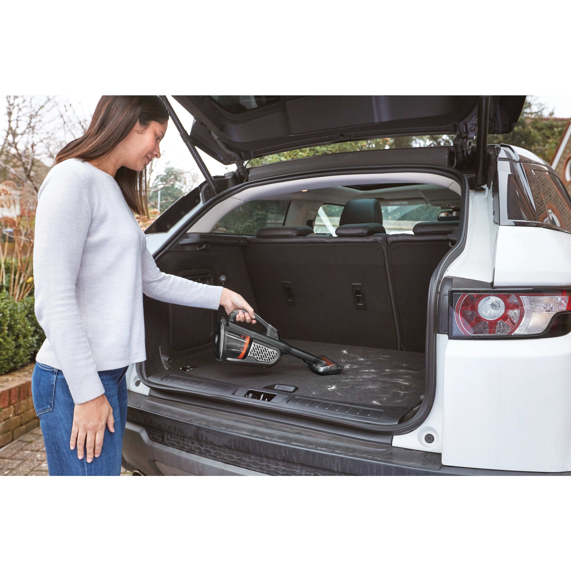 12 volt MAX dustbuster AdvancedClean cordless hand vacuum with powered pet head being used by a person to clean car trunk.