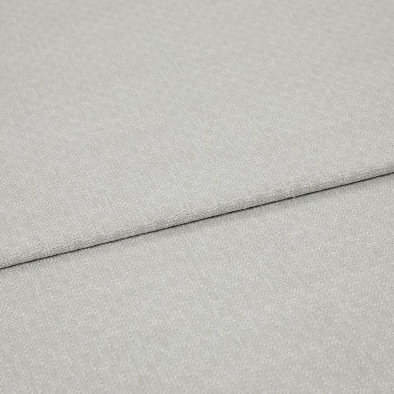 Light grey textured fabric panels overlapping slightly; top panel folded along a seam. Close-up view emphasizing woven pebble pattern, soft matte lighting, minimal background, studio-like neutral setting.