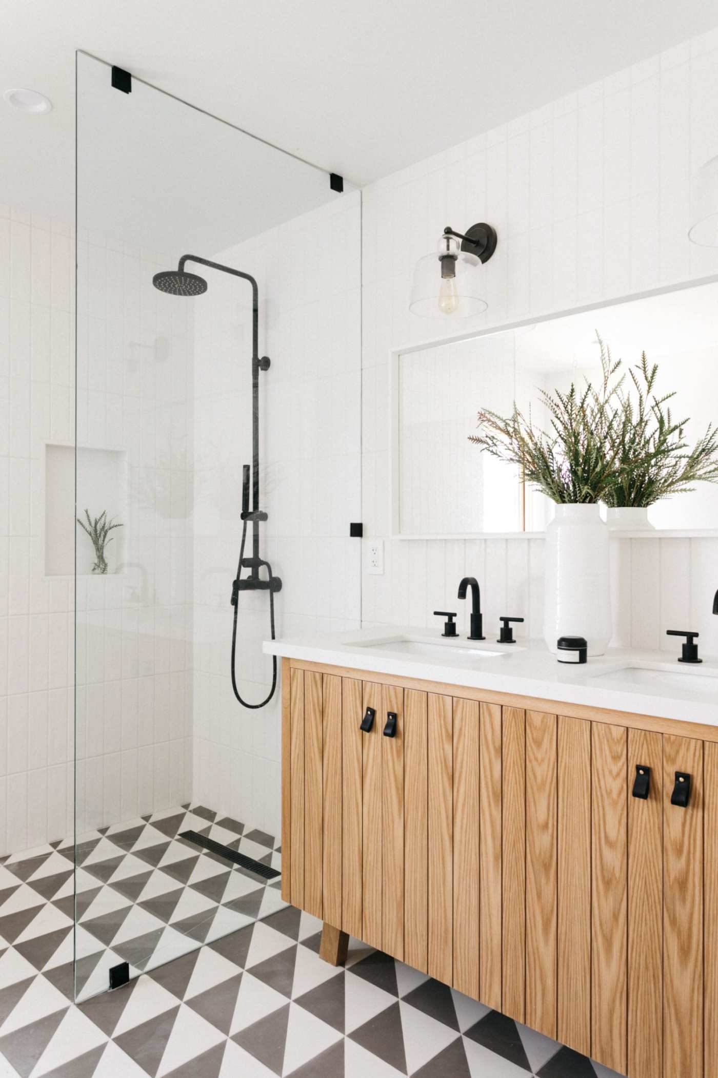 a bathroom with a black and white tile floor and a glass shower.