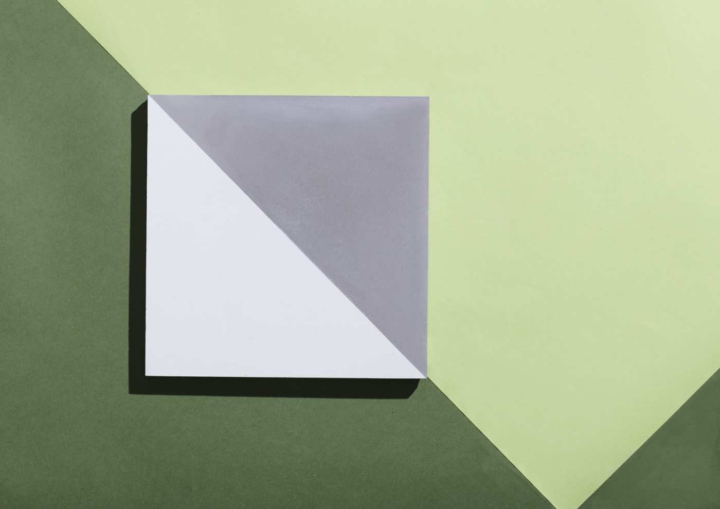 a white and grey tile on a multicolored green background.