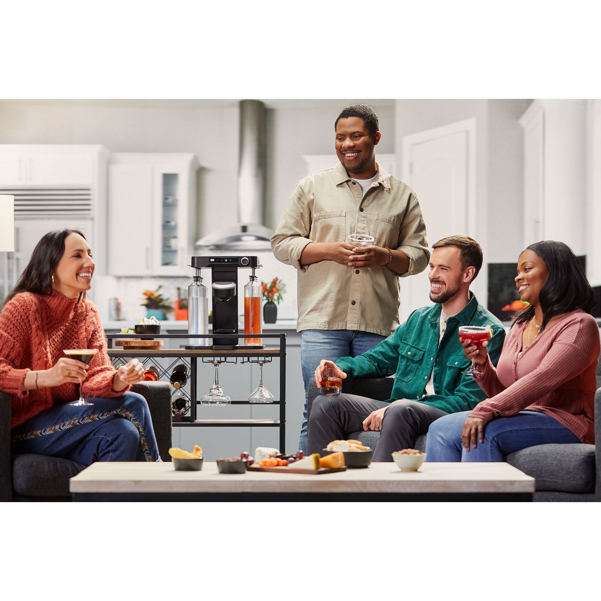 a group of friends hanging out in a living room enjoying their drinks made by the bev by BLACK+DECKER™ cordless cocktail maker that sits on a bar cart