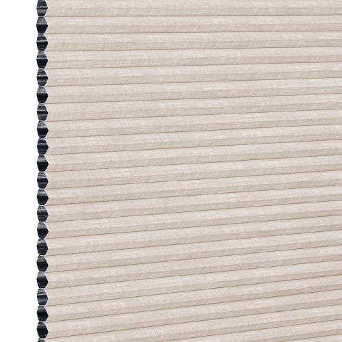 Beige cellular (honeycomb) window shade, pleated and fully lowered with exposed black cell openings along the left edge, blocking light and showing a textured fabric surface against a white background.