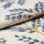 Cream woven curtain fabric with raised blue floral motifs and gold-thread stems â€” folded and layered, showing textured weave â€” close-up studio-lit textile sample with soft, neutral background.