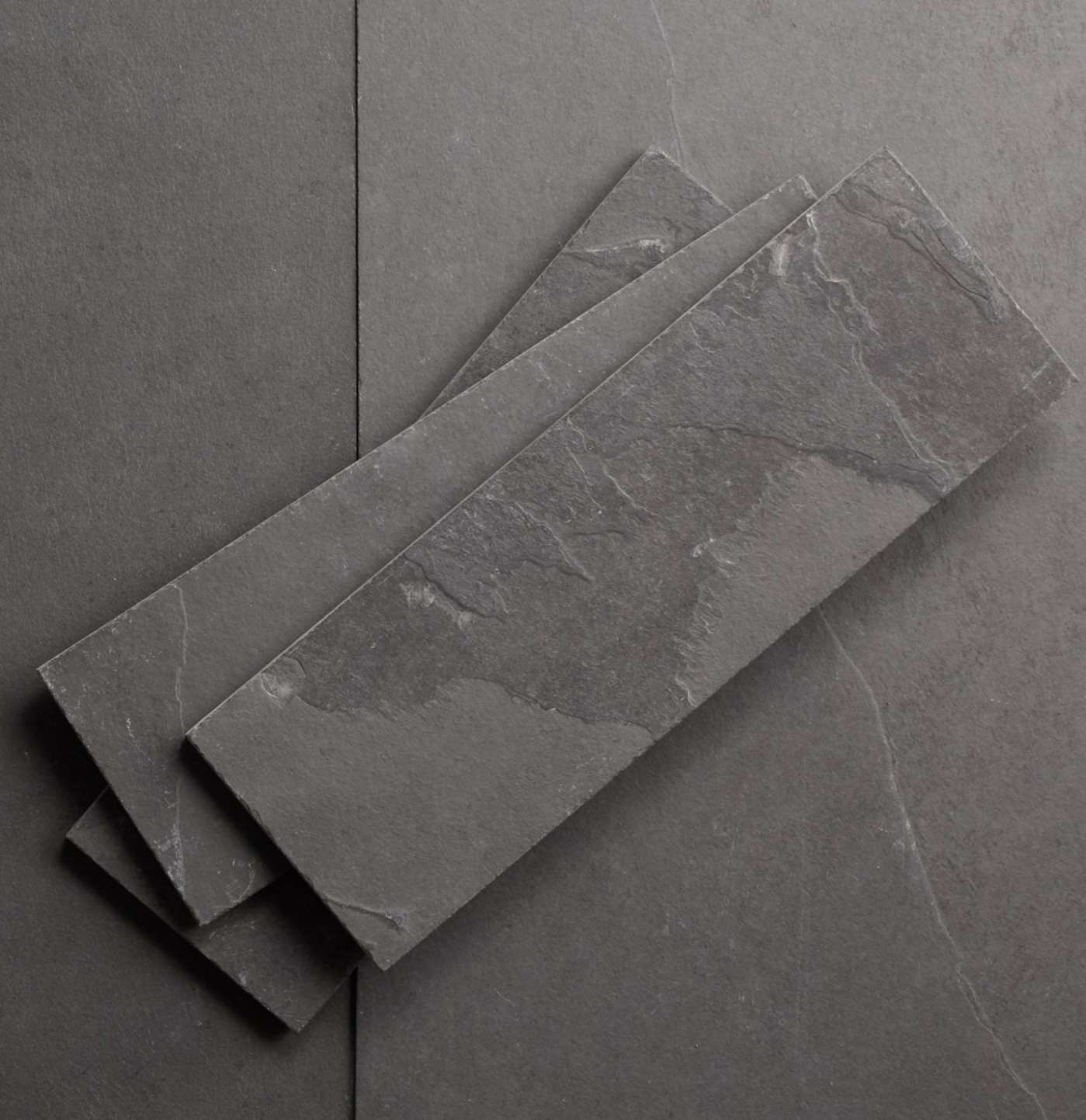 three grey slate tiles laid out on a grey surface.