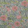 Floral printed fabric or wallpaper covering a flat surface, showing large pink peonies, green leaves and tiny blue sprigs; pattern repeats densely, evenly lit close-up decorative surface.